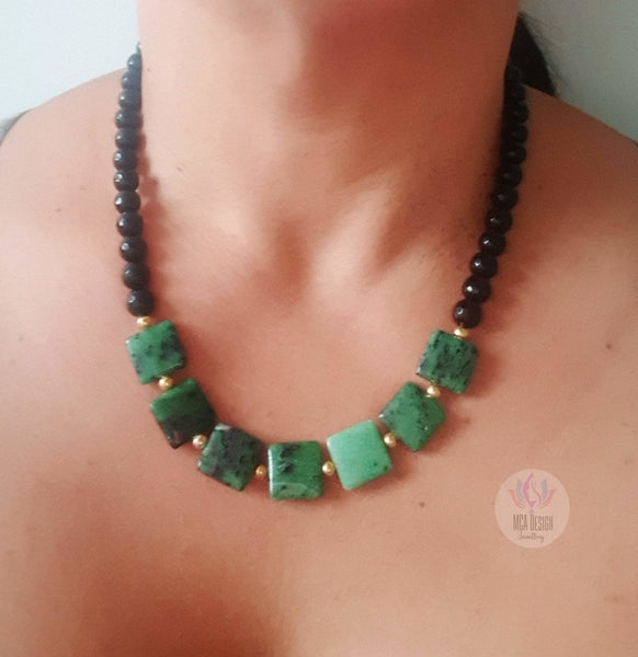 A close-up image of a woman wearing a Ruby Zoisite and Obsidian Necklace with gold-plated spacers.